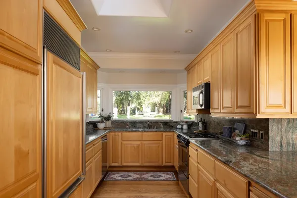 a kitchen with stainless steel appliances granite countertop a refrigerator a sink a stove and white cabinets