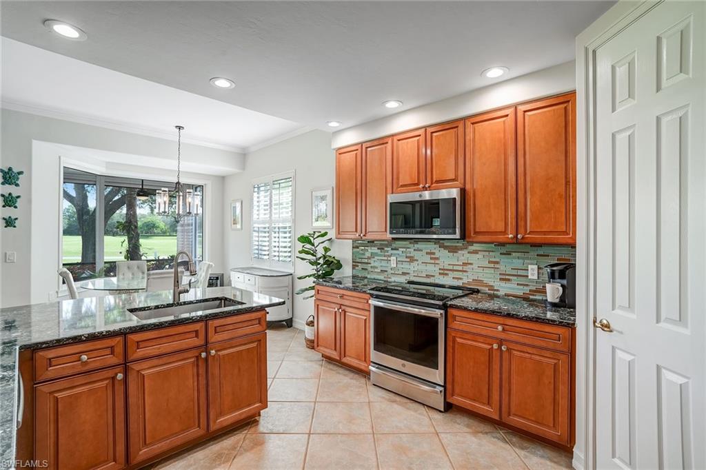 9350 Triana Terrace, Unit 292 Fort Myers, FL 33912 - Photo 11 of 28 a kitchen with stainless steel appliances granite countertop wooden cabinets and a stove top oven