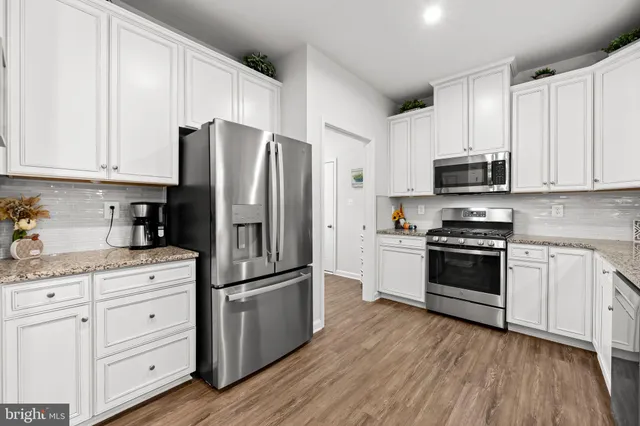 a kitchen with stainless steel appliances a refrigerator and a wooden floor