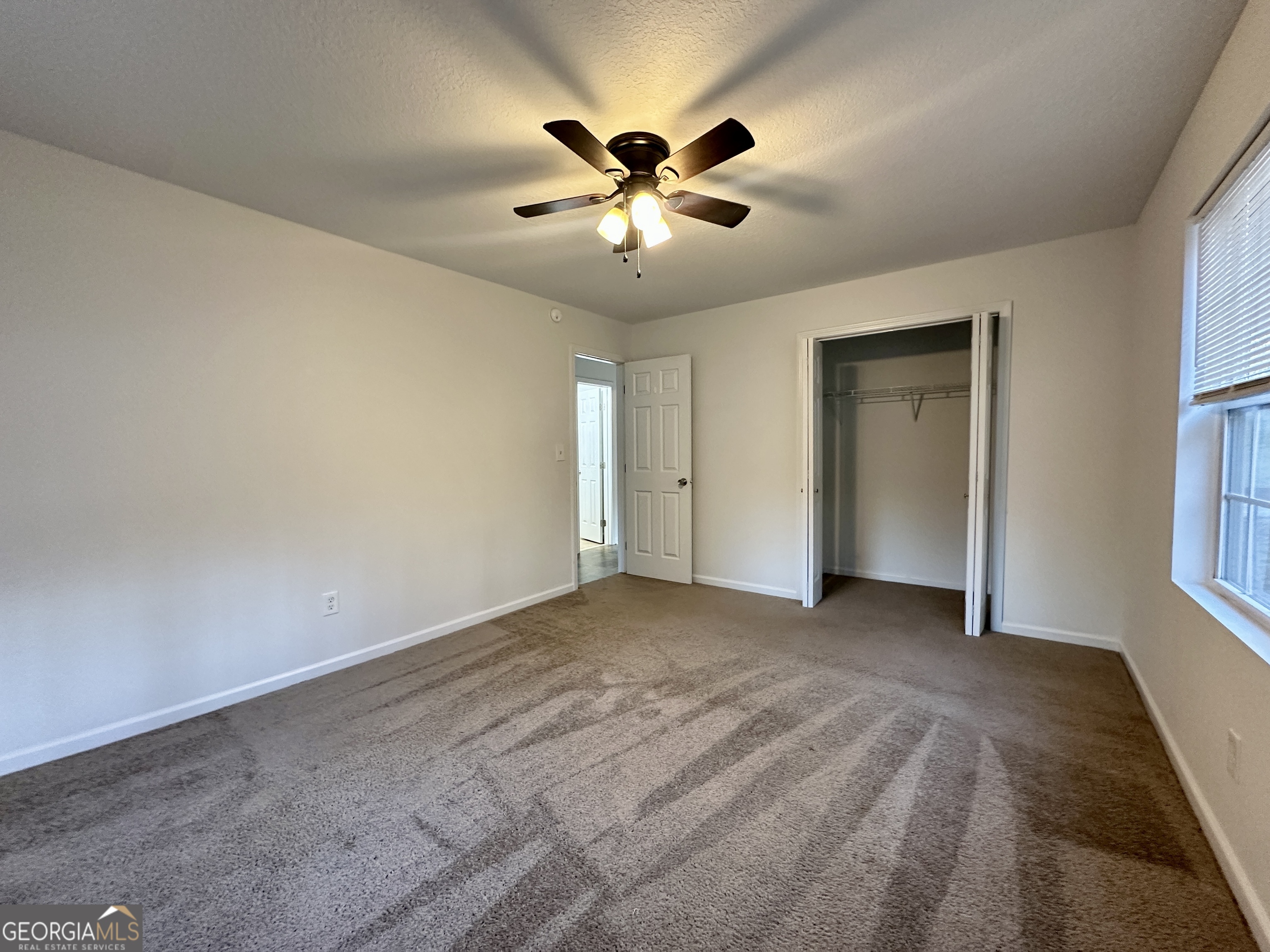 122 Forest Avenue Commerce, GA 30529 - Photo 11 of 17 a view of an empty room with a ceiling fan and window