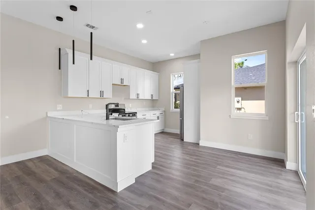 a kitchen with stainless steel appliances granite countertop a refrigerator a sink dishwasher a stove and white countertops with wooden floor