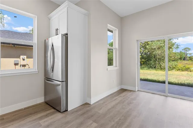 a view of kitchen with stainless steel appliances wooden floor and window