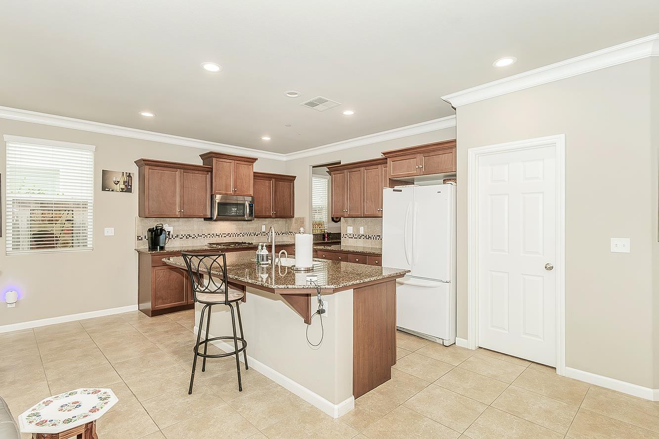 7133 North Generation Drive Fresno, CA 93711 - Photo 2 of 38 a kitchen with stainless steel appliances kitchen island granite countertop a refrigerator and a stove top oven