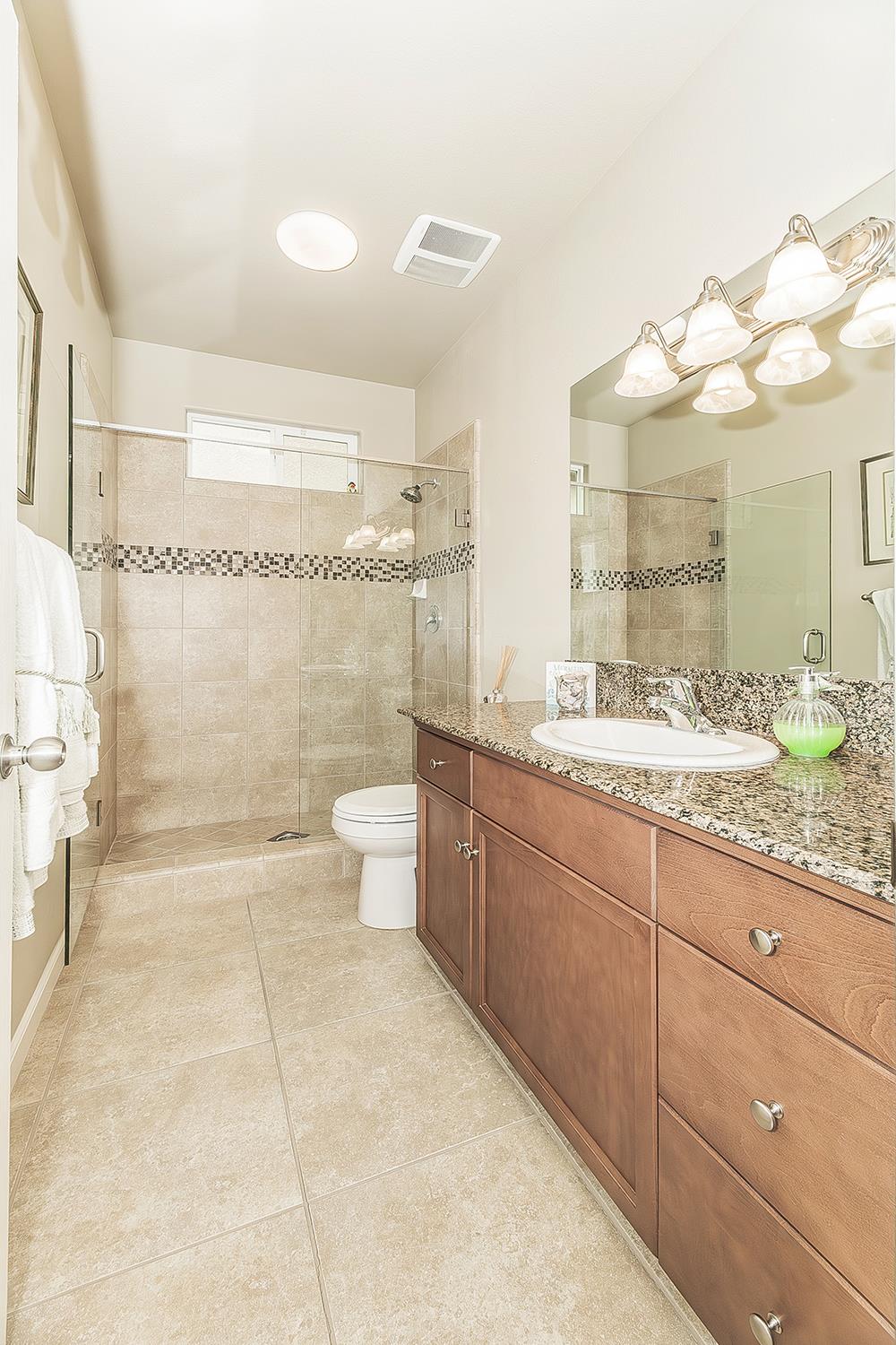 7133 North Generation Drive Fresno, CA 93711 - Photo 30 of 38 a bathroom with a granite countertop sink a toilet and a shower
