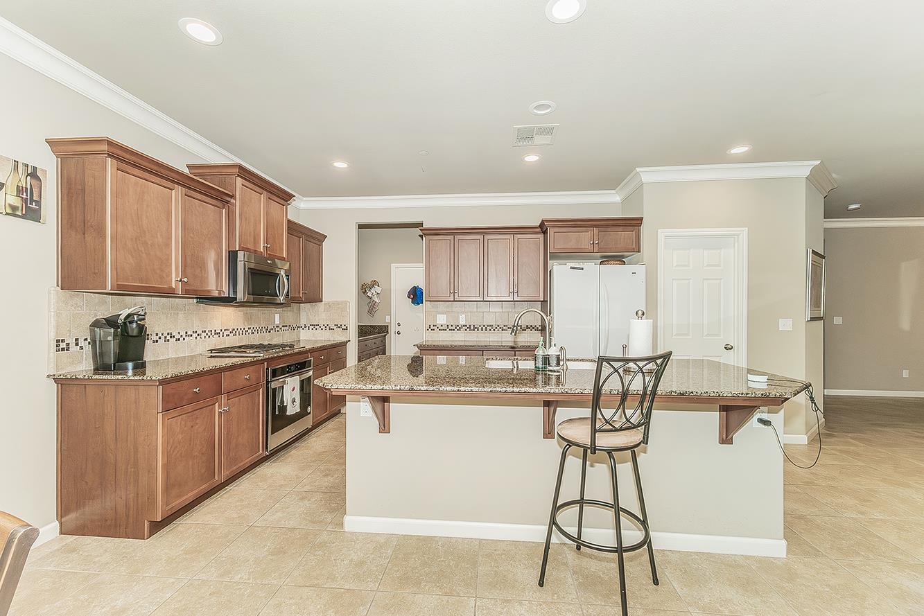 7133 North Generation Drive Fresno, CA 93711 - Photo 3 of 38 a kitchen with stainless steel appliances kitchen island granite countertop a refrigerator and a stove top oven