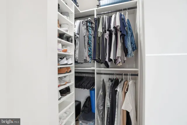 a view of walk in closet with clothes and shoes