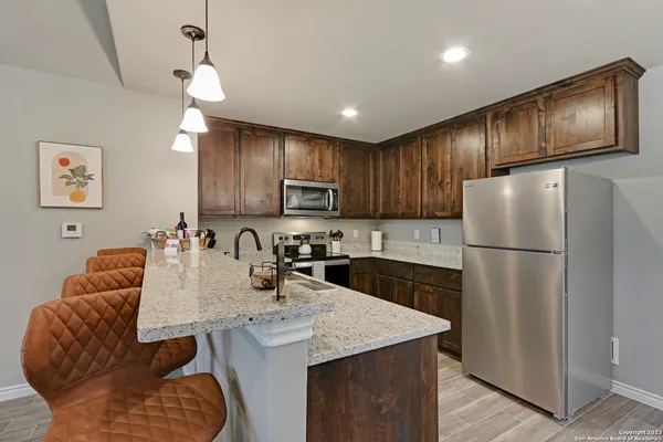 a kitchen with stainless steel appliances granite countertop a refrigerator a sink dishwasher a stove with wooden cabinets and floor