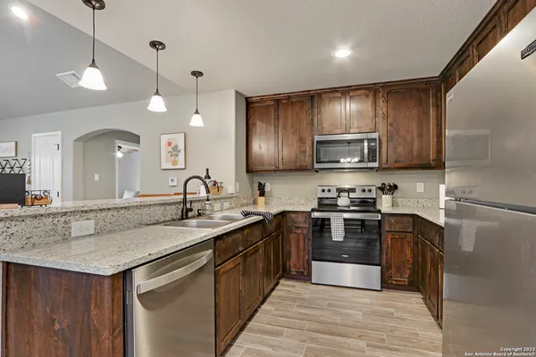 a kitchen with stainless steel appliances granite countertop a sink a stove top oven and wooden floors