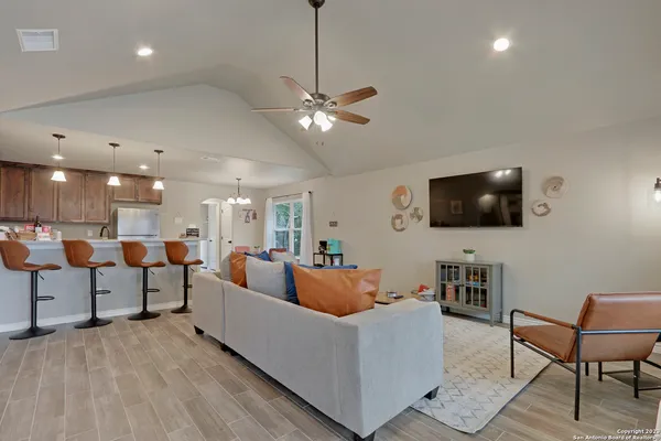 a living room with furniture kitchen view and a flat screen tv