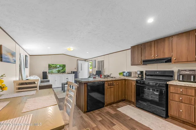 a kitchen with stainless steel appliances granite countertop a stove top oven a sink dishwasher and white cabinets with wooden floor