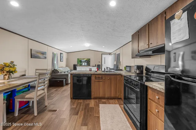 a kitchen with stainless steel appliances granite countertop a stove top oven a sink dishwasher and cabinets with wooden floor