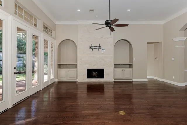 a view of an empty room with wooden floor and a window