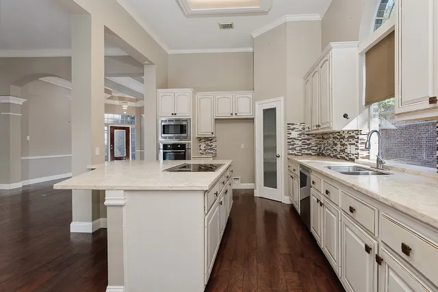 a view of a kitchen with stainless steel appliances granite countertop a stove top oven a sink and a view of living room