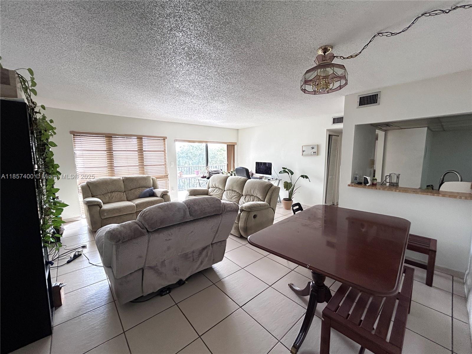 14201 Southwest 66th Street, Unit 306 Miami, FL 33183 - Photo 5 of 38 a living room with furniture a chandelier and a dining table