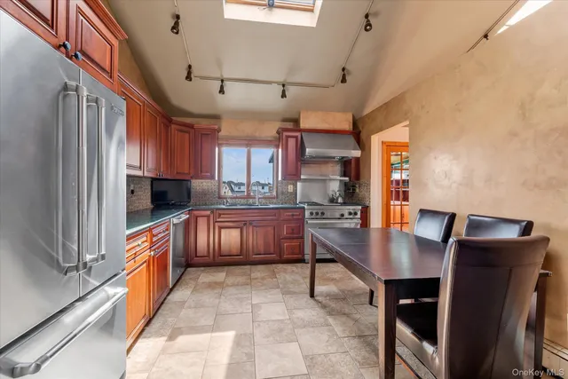 a kitchen with stainless steel appliances granite countertop a sink a stove and a refrigerator