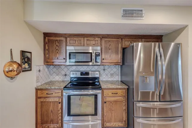 a kitchen with appliances a refrigerator and a stove top oven