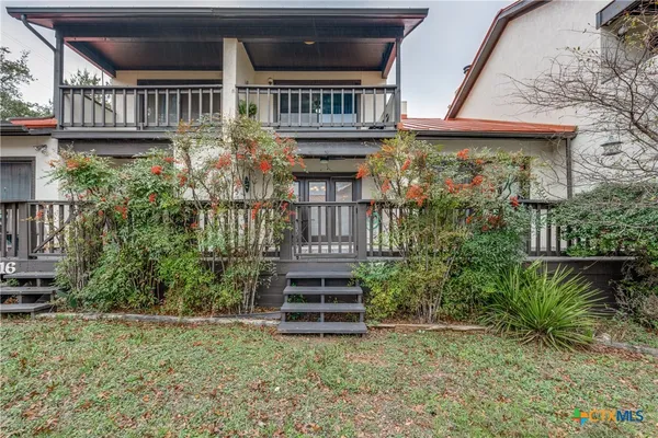 a view of a house with large windows and flower plants