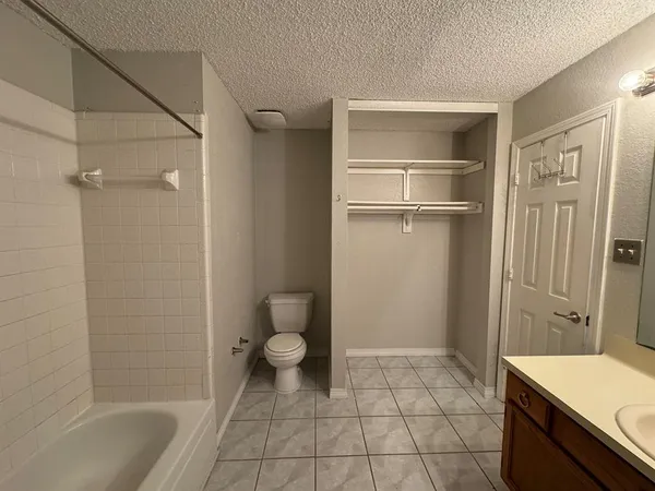 a bathroom with a granite countertop bathtub shower and toilet