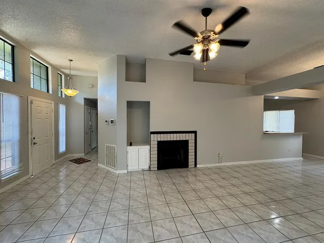 a view of an empty room with a ceiling fan and a fireplace