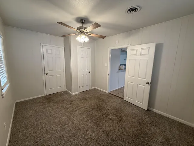 an empty room with closet and a chandelier fan