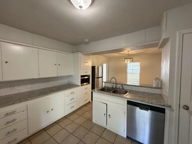 a kitchen with granite countertop white cabinets white appliances and granite counter tops