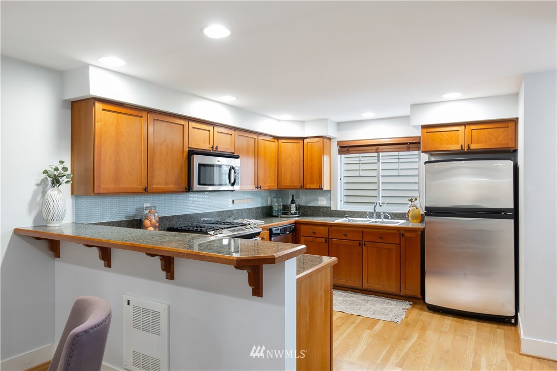 10303 Holman Road North, Unit A Seattle, WA 98177 - Photo 16 of 40 a kitchen with stainless steel appliances granite countertop a refrigerator a sink a stove a table and chairs