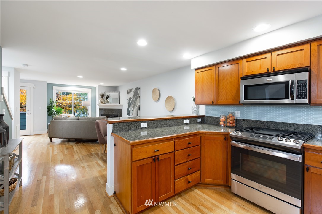 10303 Holman Road North, Unit A Seattle, WA 98177 - Photo 17 of 40 a kitchen with stainless steel appliances granite countertop a stove a sink and a microwave