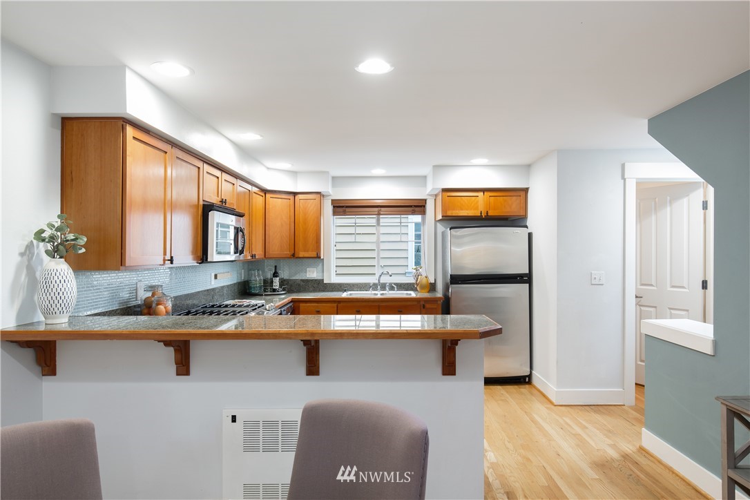 10303 Holman Road North, Unit A Seattle, WA 98177 - Photo 18 of 40 a kitchen with stainless steel appliances granite countertop a sink and a refrigerator