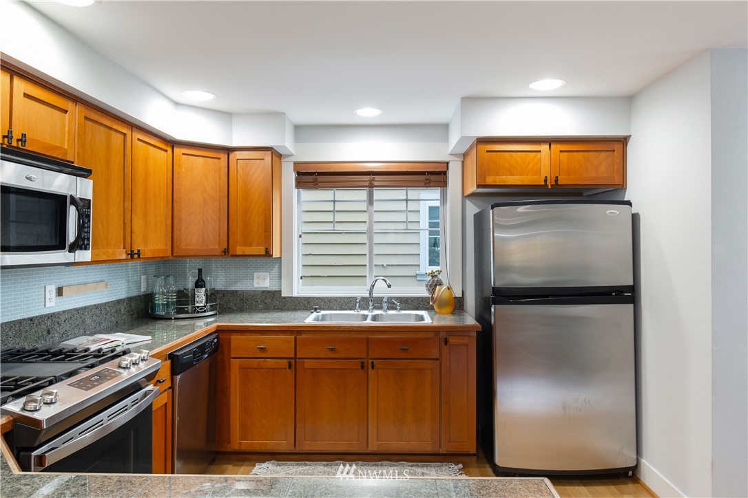 10303 Holman Road North, Unit A Seattle, WA 98177 - Photo 19 of 40 a kitchen with stainless steel appliances granite countertop a refrigerator a stove and a sink
