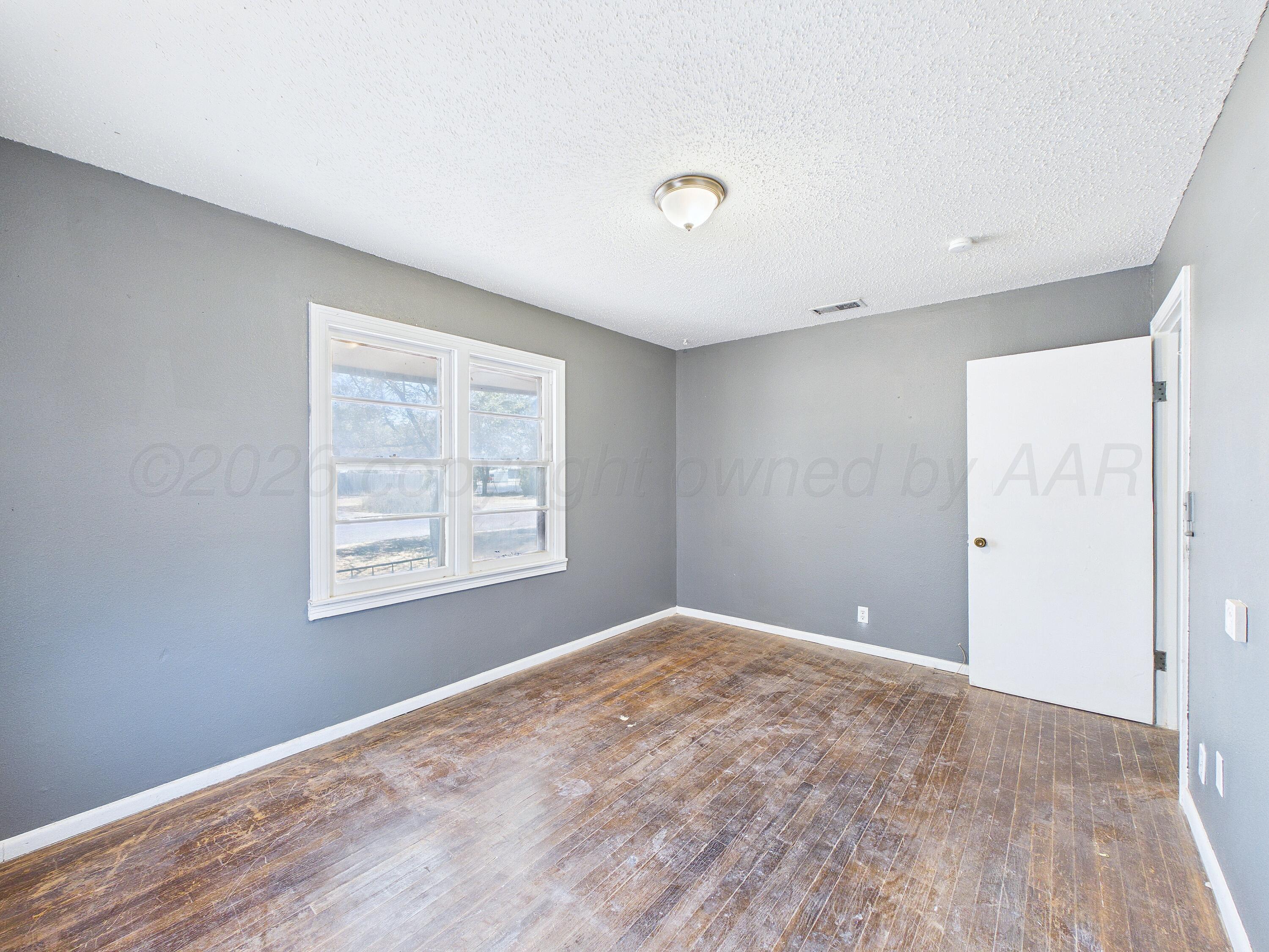 4311 Bowie Street Amarillo, TX 79110 - Photo 35 of 36 a view of an empty room with wooden floor and a window