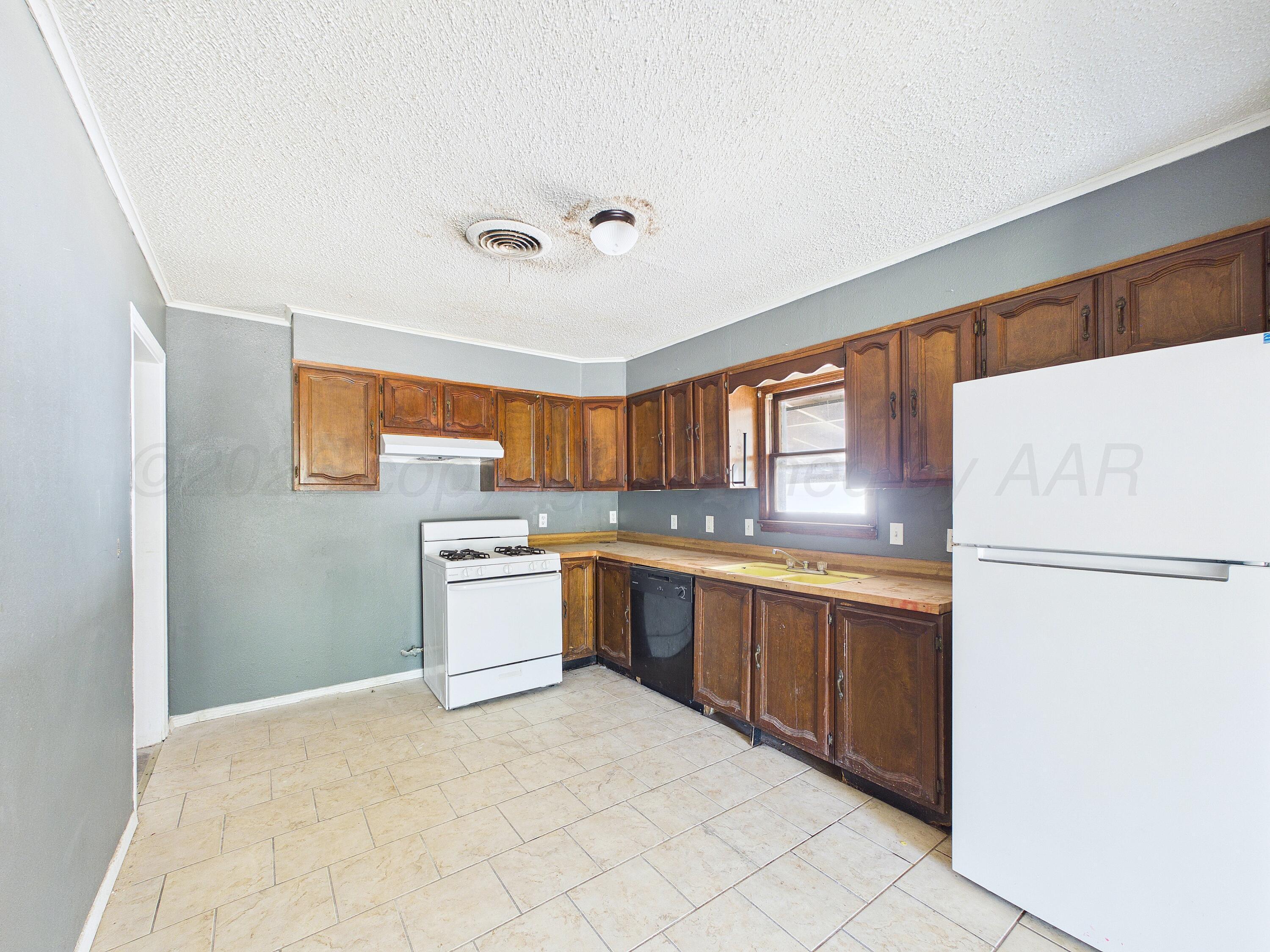 4311 Bowie Street Amarillo, TX 79110 - Photo 8 of 36 a kitchen with granite countertop appliances a sink and a refrigerator