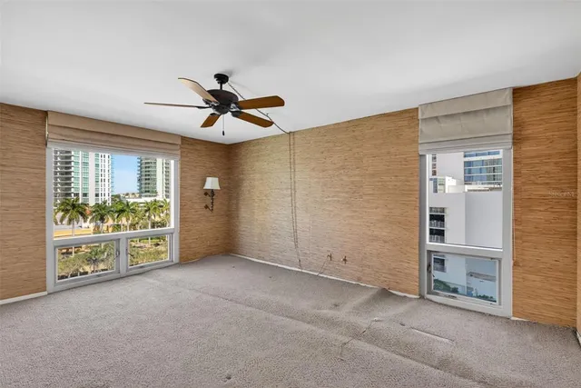 an empty room with chandelier fan and windows