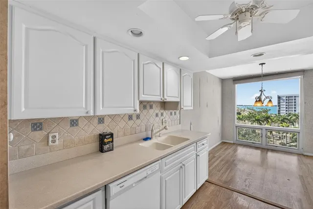 a kitchen with stainless steel appliances granite countertop a sink a window and white cabinets