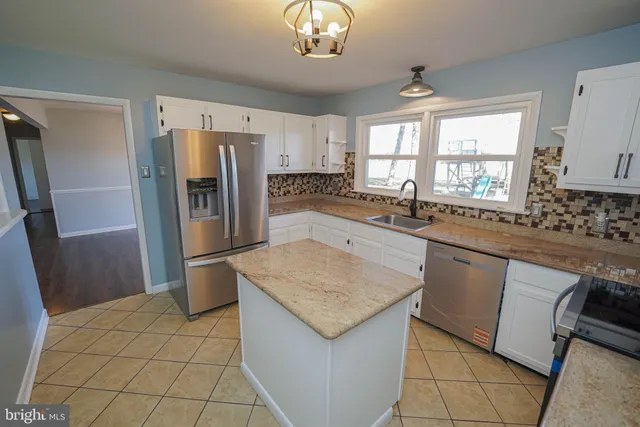 a kitchen with stainless steel appliances granite countertop a refrigerator a sink a stove a washer dryer and a cabinets