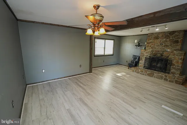 a view of an empty room with a fireplace and a window
