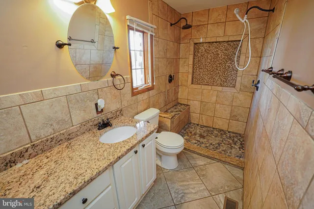 a bathroom with a granite countertop sink a toilet and shower