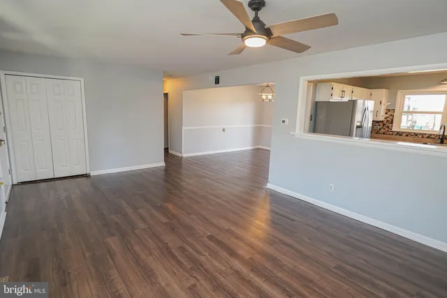 an empty room with wooden floor fan and windows