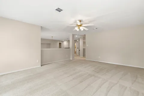 an empty room with chandelier fan and windows