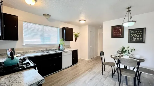 a kitchen with granite countertop a sink stove and refrigerator