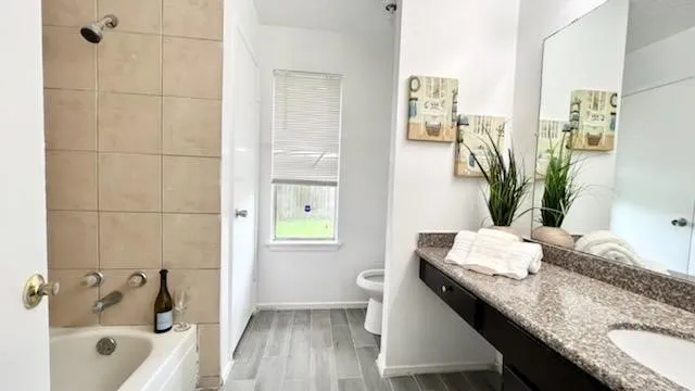 a bathroom with a granite countertop sink a toilet and shower