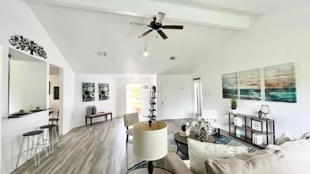 a living room with furniture large window and wooden floor