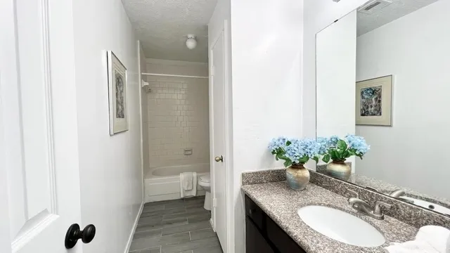 a bathroom with a granite countertop sink a toilet and shower
