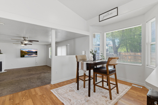 134 West 475 South Ogden, UT 84404 - Photo 5 of 27 Dining space with light wood-style flooring, a tiled fireplace, lofted ceiling, and a ceiling fan