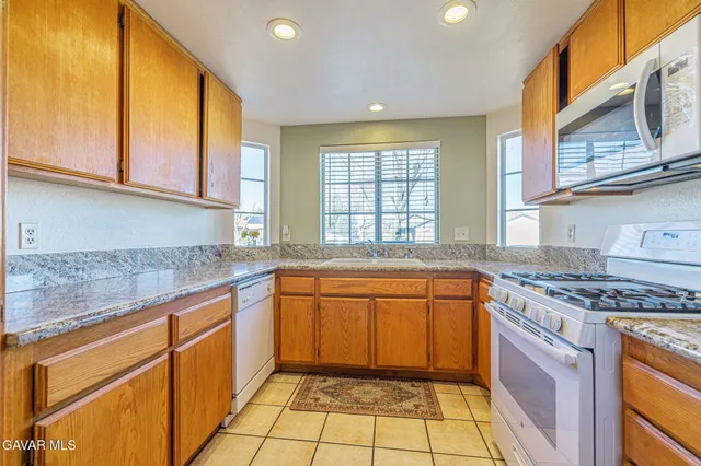 a kitchen with stainless steel appliances granite countertop a stove a sink and a microwave