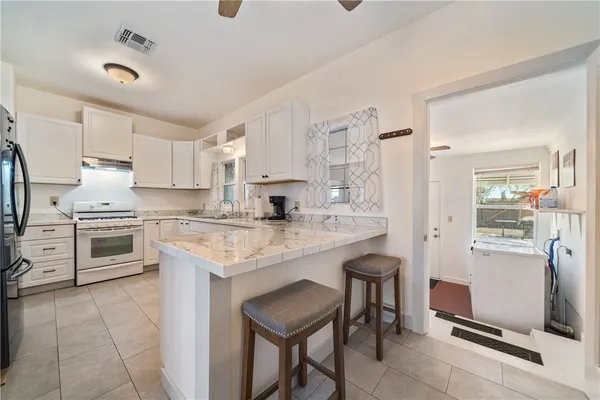 a kitchen with stainless steel appliances kitchen island granite countertop a table chairs sink refrigerator and cabinets