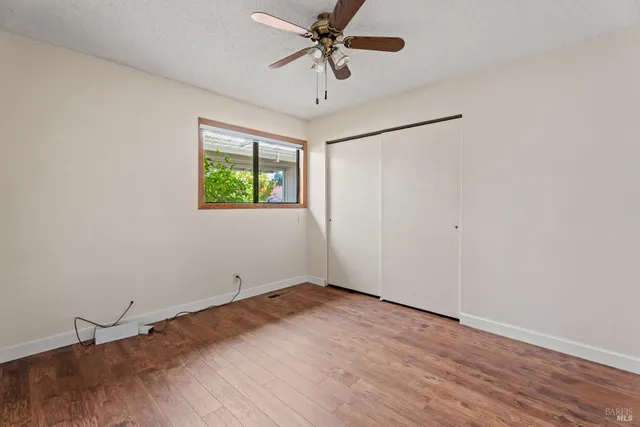 an empty room with windows and fan