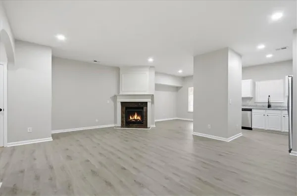 a view of an empty room with wooden floor fireplace and a window