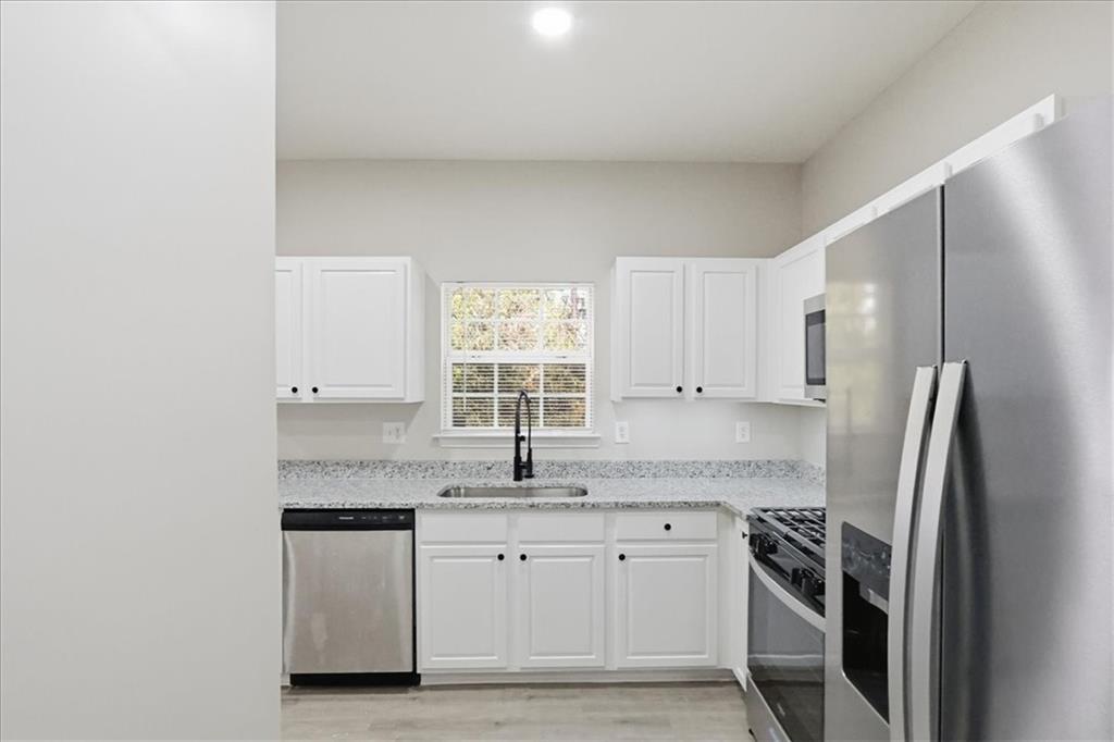 5630 Lawley Road Alpharetta, GA 30022 - Photo 24 of 65 a kitchen with granite countertop a sink stainless steel appliances and white cabinets