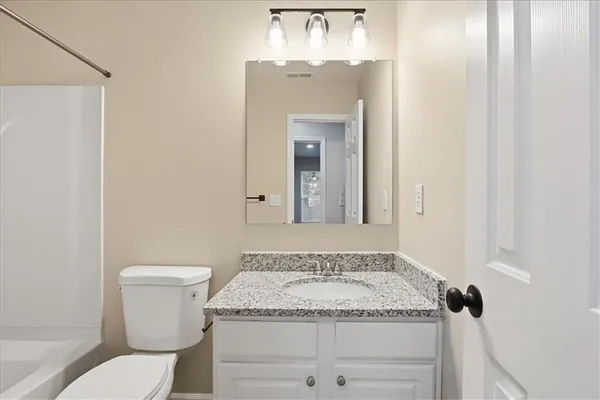 a bathroom with a granite countertop sink and white cabinets