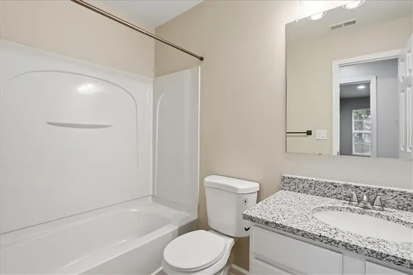 a bathroom with a granite countertop vanity and a mirror
